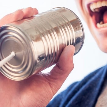 A man speaking into a tin can. It's just like using video marketing to achieve your goals.