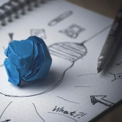 a scrunched up ball of blue paper on top of a doodle of a lightbulb