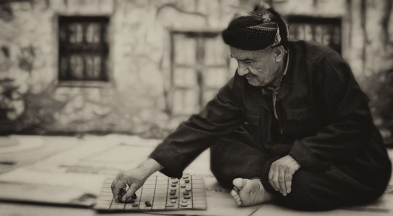 An old man playing some sort of board game. He wishes he was doing something cooler.