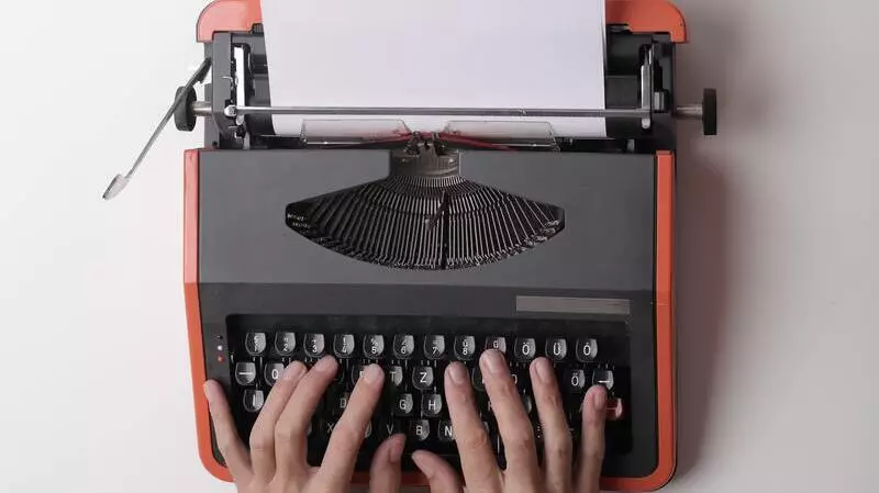 two hands typing on an orange typewriter against a white background